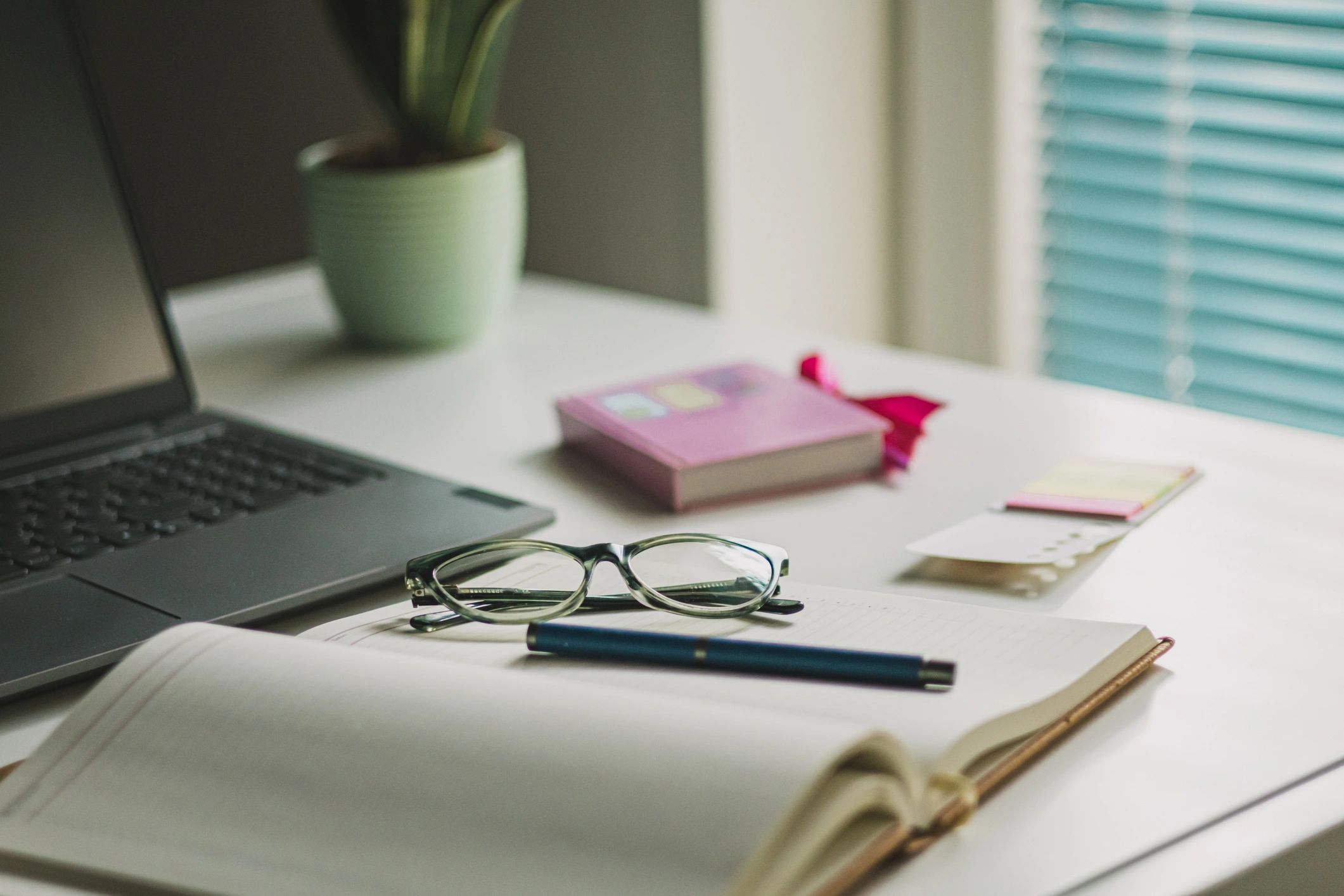 Office desk table with laptop, coffee, and glasses