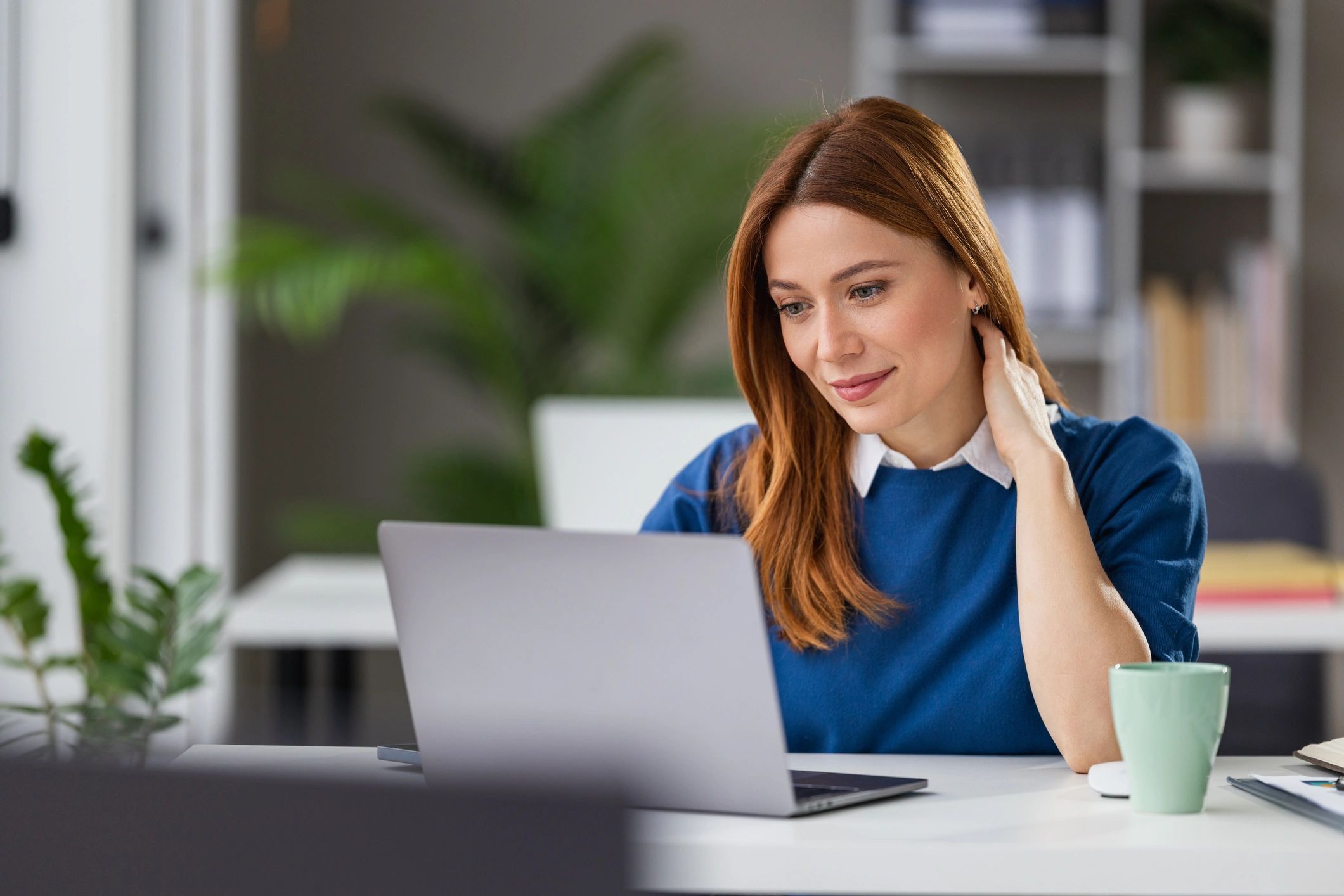 Woman working on laptop at home office smiling while focused on screen